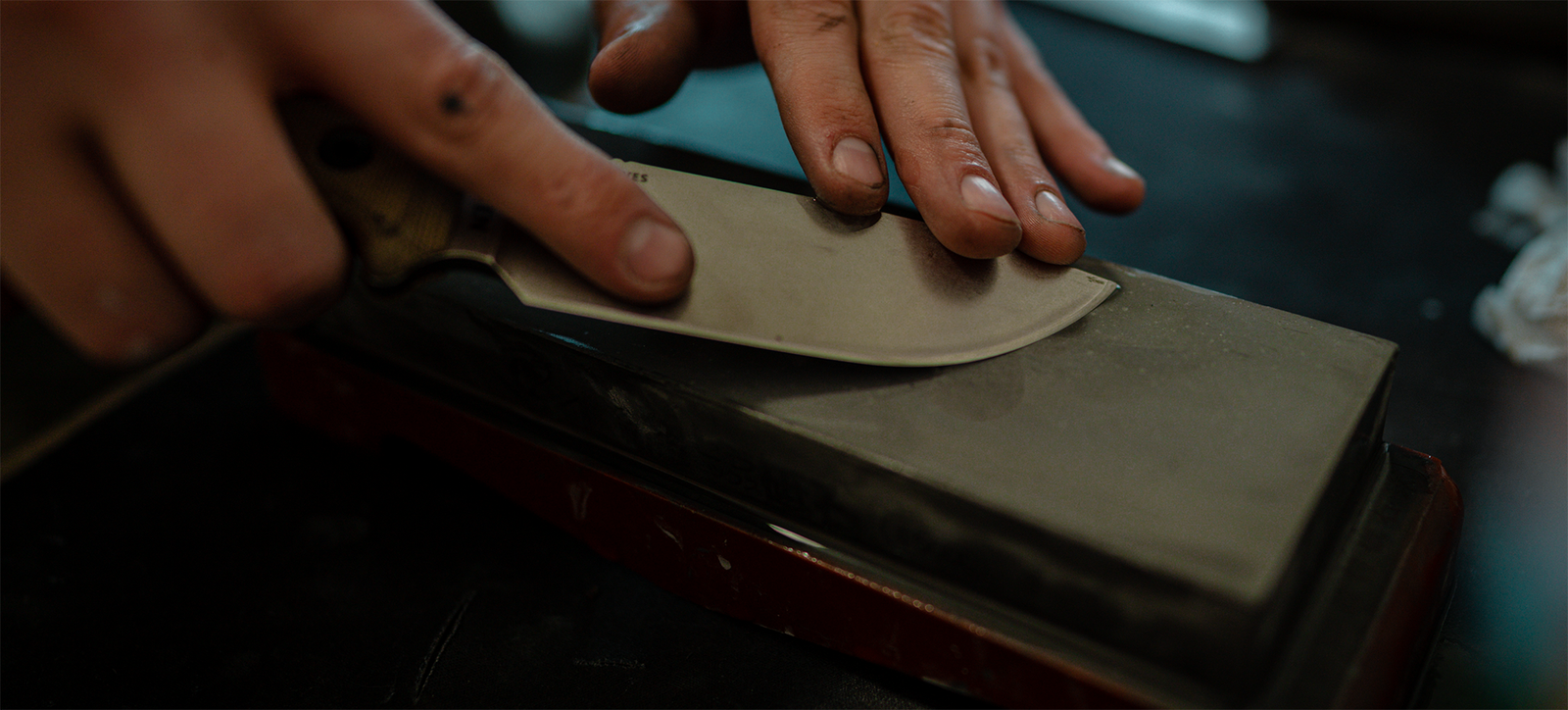Sharpening a knife blade by hand on a whetstone at Timber Knives